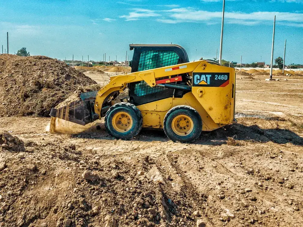 A skid steer grading an open dirt lot (representative photo)