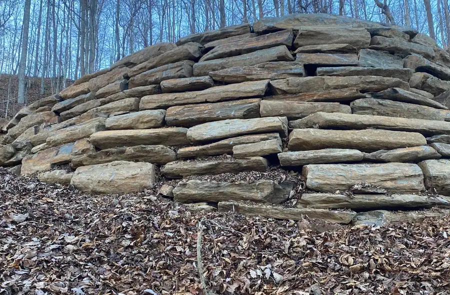 Dry-stacked stone wall built into a wooded hillside by Superior Land Services